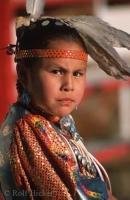 A First Nations girl dressed in traditional native clothing poses for a picture.