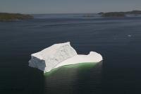A large iceberg is sitting along the Kittiwake coast in Newfoundland seen from a plane, aerial view.