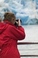 A female tourist photographing a glacier on her vacation in the Juneau area.