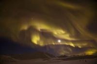 Aurora borealis dancing over snowcapped mountains on a Yukon vacation, Canada.