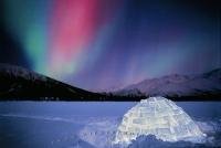 Northern Lights dancing above an igloo on a cold winter day in northern Alaska.