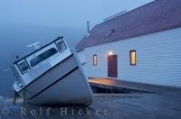 In the historic fishing village of Battle Harbour in Southern Labrador, Canada, the fog starts to settle in around the island and along the wharf sits an old fishing boat.