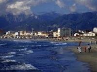 The town of Viareggio with high mountains in the background and the town beach with people in the foreground, Toskany, Italy