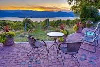 A beautiful sunset adorns the evening sky above Okanagan Lake and a patio setting at a vineyard in Naramata in the Okanagan-Similkameen region of British Columbia, Canada.