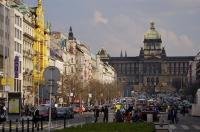 In front of the historic buildings, one being the National Museum, the street is very busy as cars and people fill the area of downtown Prague in the Czech Republic to visit Wenceslas Square.