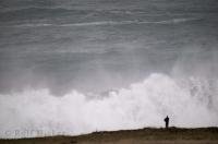 A person is dwarfed with a background of waves along the California Coast in the USA.