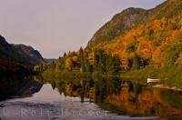 A picture of typical Canadian landscape during the autumn season in Quebec. Colours of fall cloak the mountain sides and reflect on the still waters.