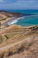 Tourists get a beautiful scenic view of the Cape Kidnappers coastline off the North Island of New Zealand hiking down from the Australasian Gannet Colony.