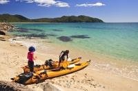 Kayakers take a rest along the Abel Tasman National Park beach front in the South Island of New Zealand. Sea kayaking is a popular tourist activity that offers spectacular views of the gorgeous coastal scenery of the park.