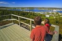 A couple enjoy a hike on a beautiful summer day ending at a platform overlooking the town of St Anthony in west Newfoundland.