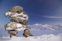 The snow covered inukshuk stands alone on a clear winter day in Alaska. The inukshuk is an ancient eskimo sign that is used as a marker in areas which are void of natural landmarks such as arctric regions.