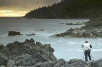 A photographer snapping photos of the ocean view from Cape Palmerston on the West Coast of Northern Vancouver Island in British Columbia, Canada.