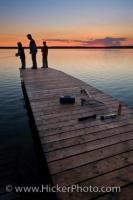 A father spends some quality time with his two sons during a fishing vacation as the sun sets in the background in Riding Mountain National Park. They are fishing in Lake Audy, which is a prime fishing spot in this park in Manitoba, Canada.