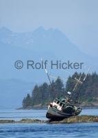 A small fishing boat at low tide on a rock.