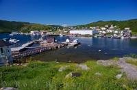 Deep blue skies and green hillsides surround the harbour of the town of Fleur De Lys along the Dorset Trail on Highway 412 in Newfoundland, Canada.