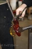 Two colors of glass are fused together during a demonstration at the Lincoln City Glass Center in Oregon, USA.
