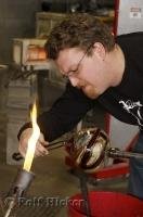 A glassblowing artist shapes the opening of a piece of art at the Lincoln City Glass Center.