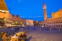 The historic old town district of Siena is one of the most popular parts of the city. In this picture the buildings are lit up at dusk as night falls on the city and people enjoy the twilight at some of the outdoor cafes.