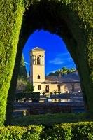The unique architecture of the Hotel San Francisco as seen through a rounded arch in the hedge in the City of Granada in Andalusia, Spain.