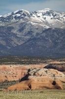 The snowcapped La Sal Mountain Range towers above the badlands of Utah, USA..