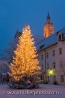 On the grounds of the Landratsmat in Neustift, Freising in Bavaria, Germany, a large Christmas tree is lit and highlights the area in yellow and golden hues.