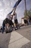 The Maibaum is raised with poles by a team of men during the Maibaumfest in Putzbrunn, Bavaria, Germany.