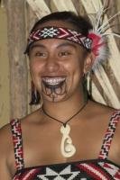 A Maori woman proudly shows her tattoo designs and maori symbols.
