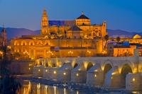 The Mezquita, also known as the Cathedral Mosque is the main tourist attraction in the city of Cordoba, in the foreground of this picture taken at dusk, is the famous Puento Romano bridge, Andalusia, Spain.