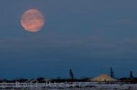 A full moon glows in a red hue over the frozen landscape in the Churchill Wildlife Management Area in Churchill, Manitoba in Canada.