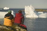 Honeymoon destinations showing a young couple in Newfoundland looking at Icebergs.