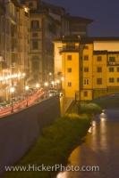 The night lights glisten along a street that runs along the riverside near the Ponte Vecchio in the City of Florence in the Region of Tuscany in Italy, Europe.