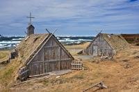 Recreated huts and buildings stand in the Norstead Viking Village along the Great Northern Peninsula of Newfoundland, Canada with pack ice floating in the harbour in the background.