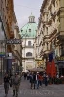 Shops and tourists fill the street in downtown Vienna, Austria with the Peterskirche prominently standing at the end.