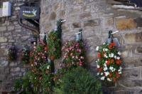 The stone walls of a restaurant in the village of Torla in Aragon, Spain are adorned with flowers that brighten up the exterior walls and the restaurant sign.