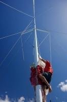 A man climbs the mast to prepare for the dropping of the sail aboard the Carino catamaran in the Bay of Islands in New Zealand.
