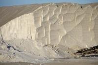 A salt cliff looms over the equipment used in this type of industry in the Parc Naturel Regional de Camargue in Provence, France.