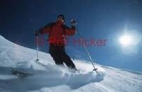 Male skier skiing down Whistler mountain in Whistler, British Columbia under beautiful clear blue sky.
