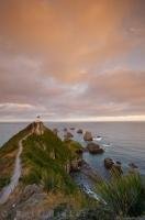 Set on a rocky headland in the Catlins district along the East Coast of the South Island of New Zealand, the Nugget Point Lighthouse faces the Pacific Ocean along a rocky stretch of coastline.