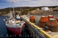 Crab pots line the dock in the harbour of St Lunaire-Griquet in Newfoundland, Canada waiting to be loaded onto this fishing boat.