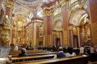 People sit in the pews surrounded by the incredible interior of the Abbey Church at the Stift Melk in Austria, Europe.
