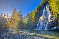Sun beams striking through the rainforest  onto a beautiful wilderness waterfall on the west coast of Vancouver Island, British Columbia, Canada.