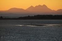 An Oregon mountain range is silhouetted by the sunrise over the mighty Columbia River seen from Ilwaco in Washington.