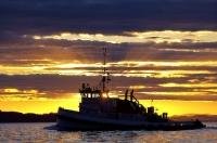 A commercial tug boat is highlighted by a gorgeous sunset off Northern Vancouver Island in British Columbia, Canada.