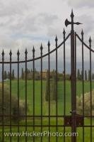 An elegant country villa nestled in the beautiful Tuscan Countryside is secured by a large wrought iron gate at the end of a driveway in the Province of Siena, Tuscany, Italy.