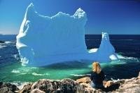 A woman sits on the rocks in the village of Twillingate, Newfoundland in Canada where an iceberg has beached itself.
