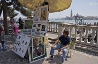 A hopeful Venetian artist showing his work along the Riva degil Schiavoni in Venice, Veneto in Italy, Europe.