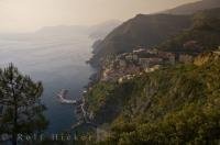 A light haze hovers across the horizon as the village of Riomaggiore in the Cinque Terre in Italy, Europe sits high on the cliffs along the coastline.